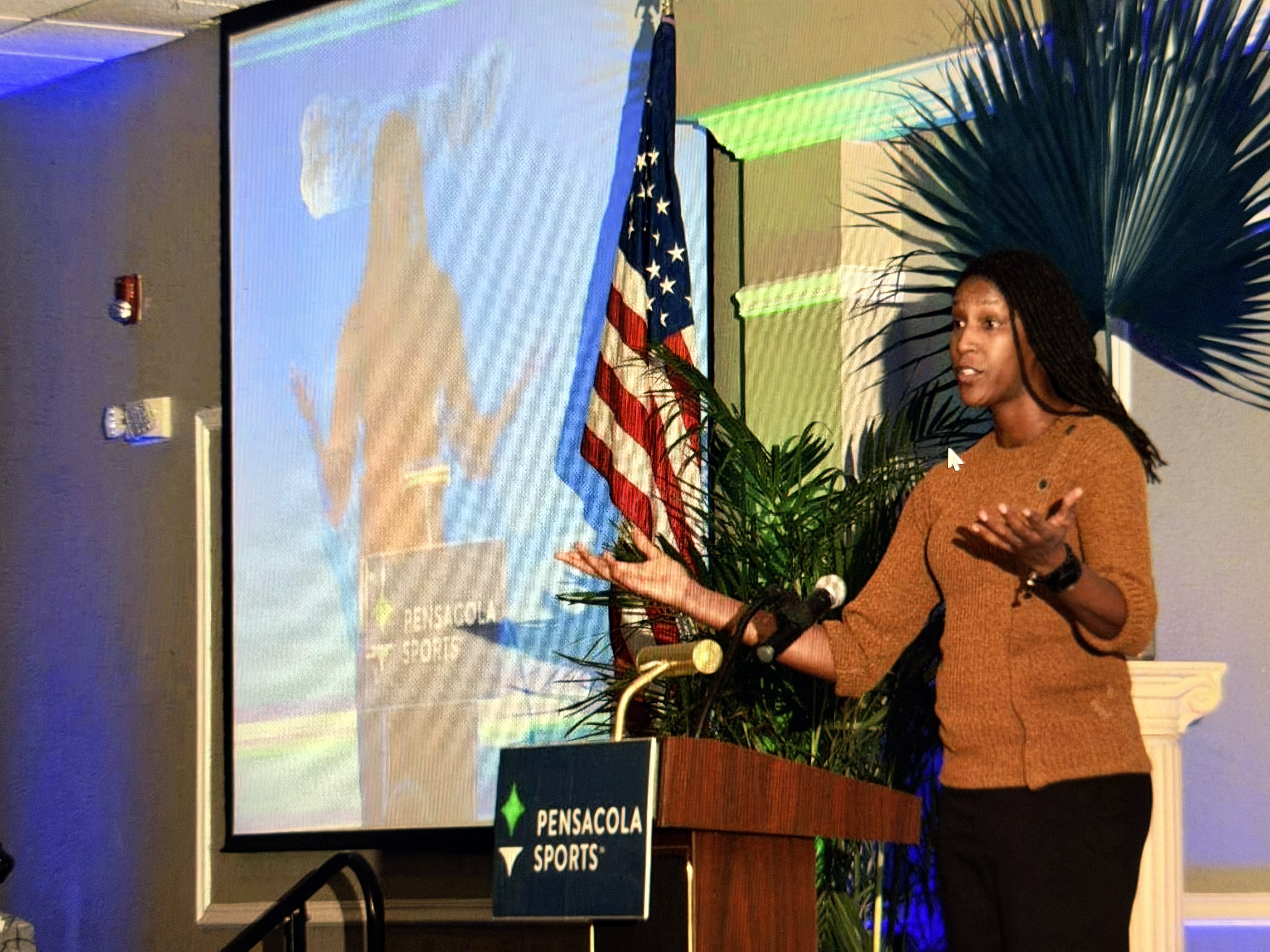 Michelle Snow delivering a keynote from the podium at a Pensacola Sports event
