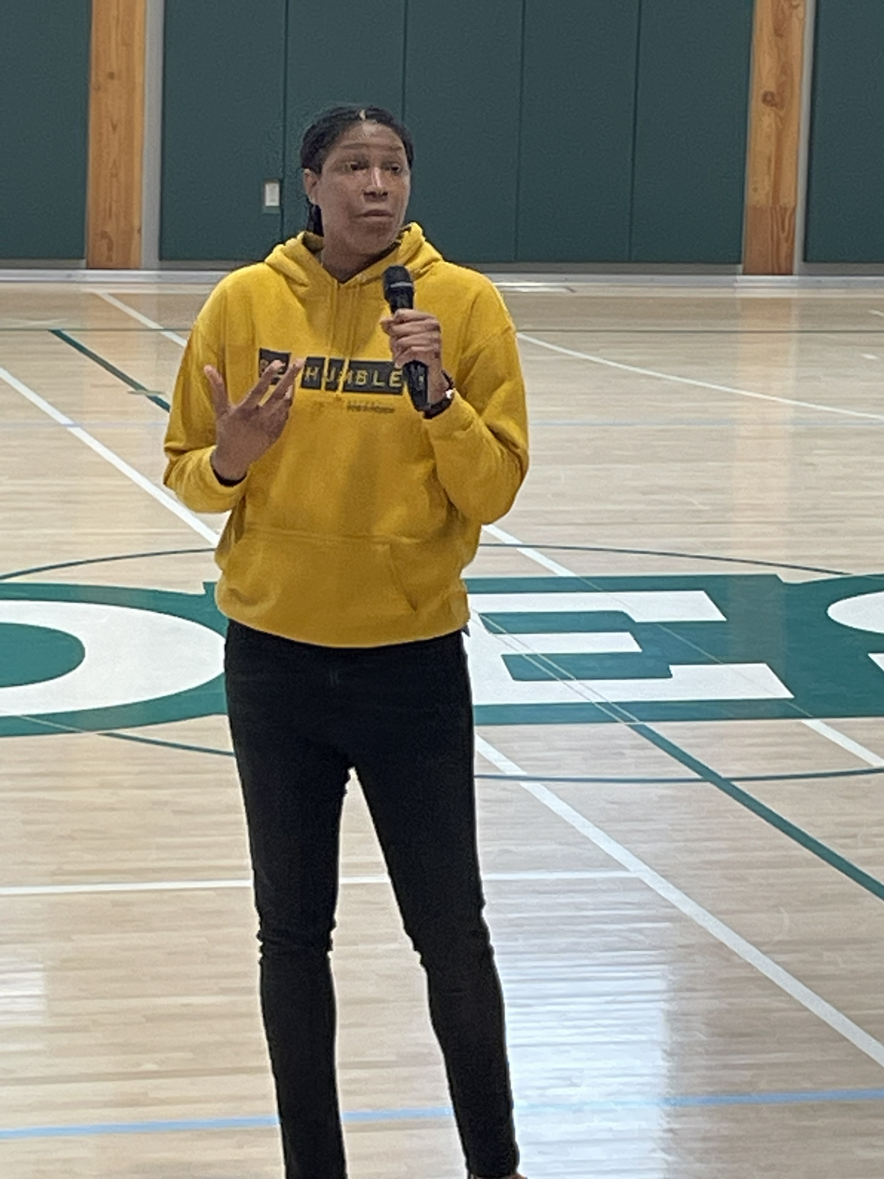 Michelle Snow speaking to students at center court in a school gymnasium