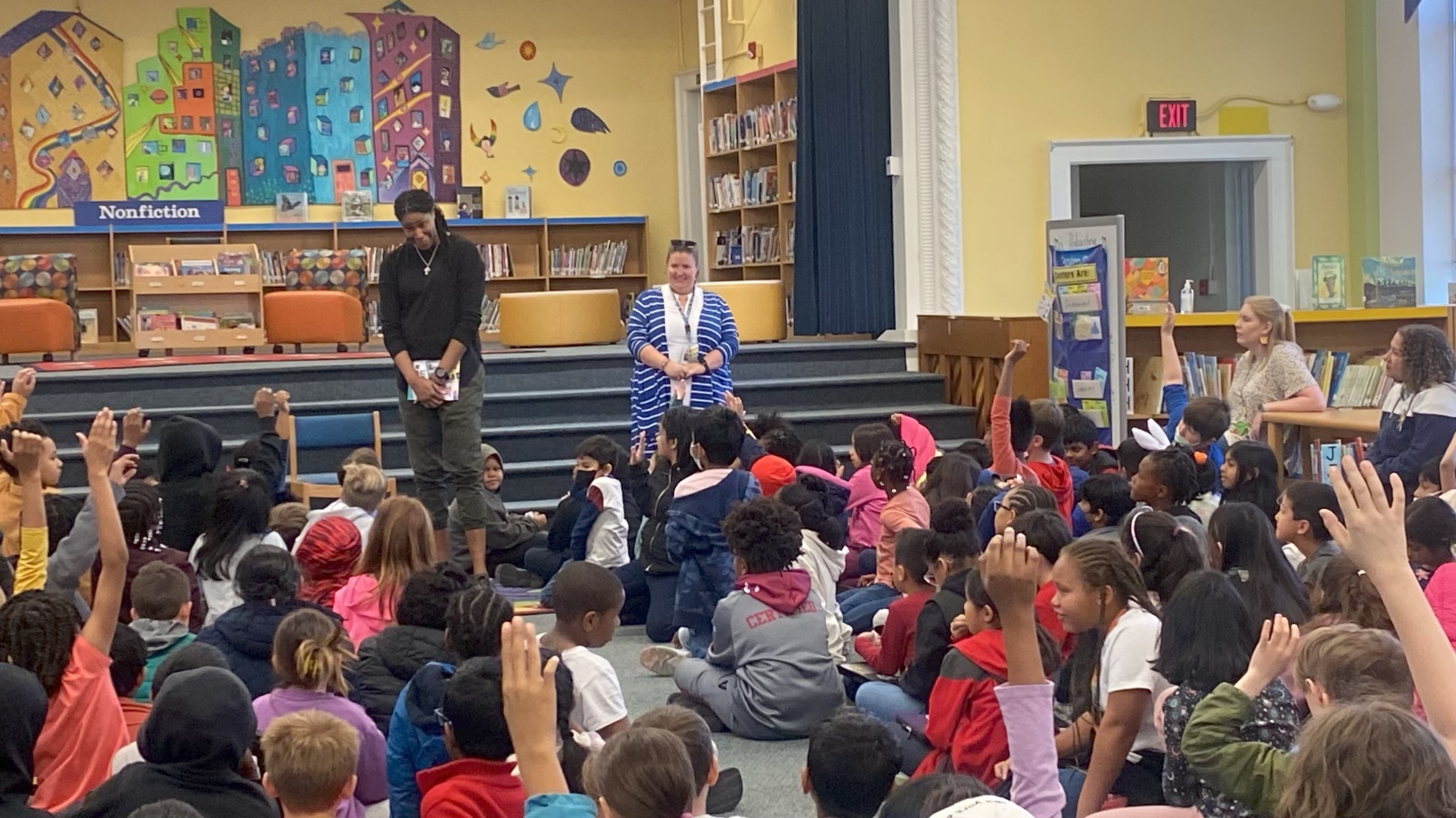 Michelle Snow in an elementary school library as children raise their hands